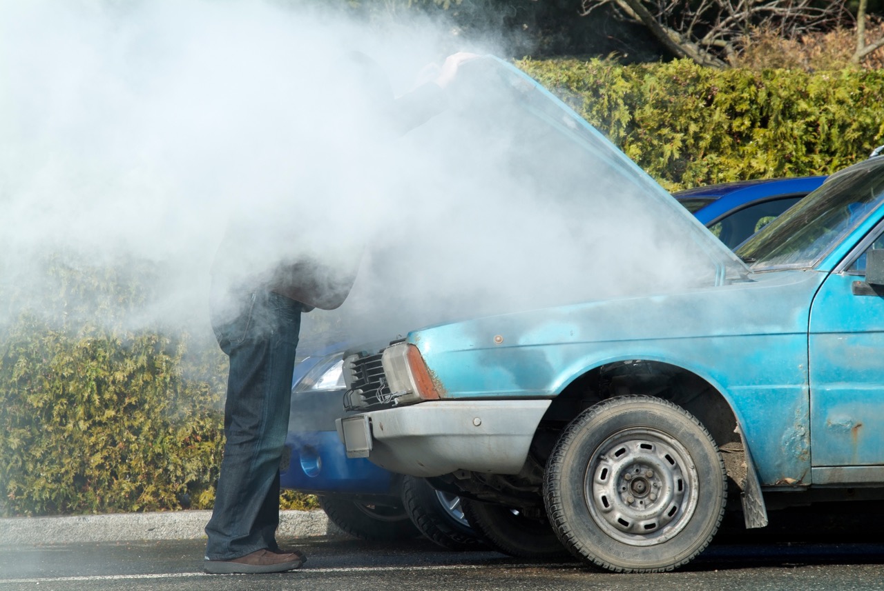 mechanic checking a smoking car engine